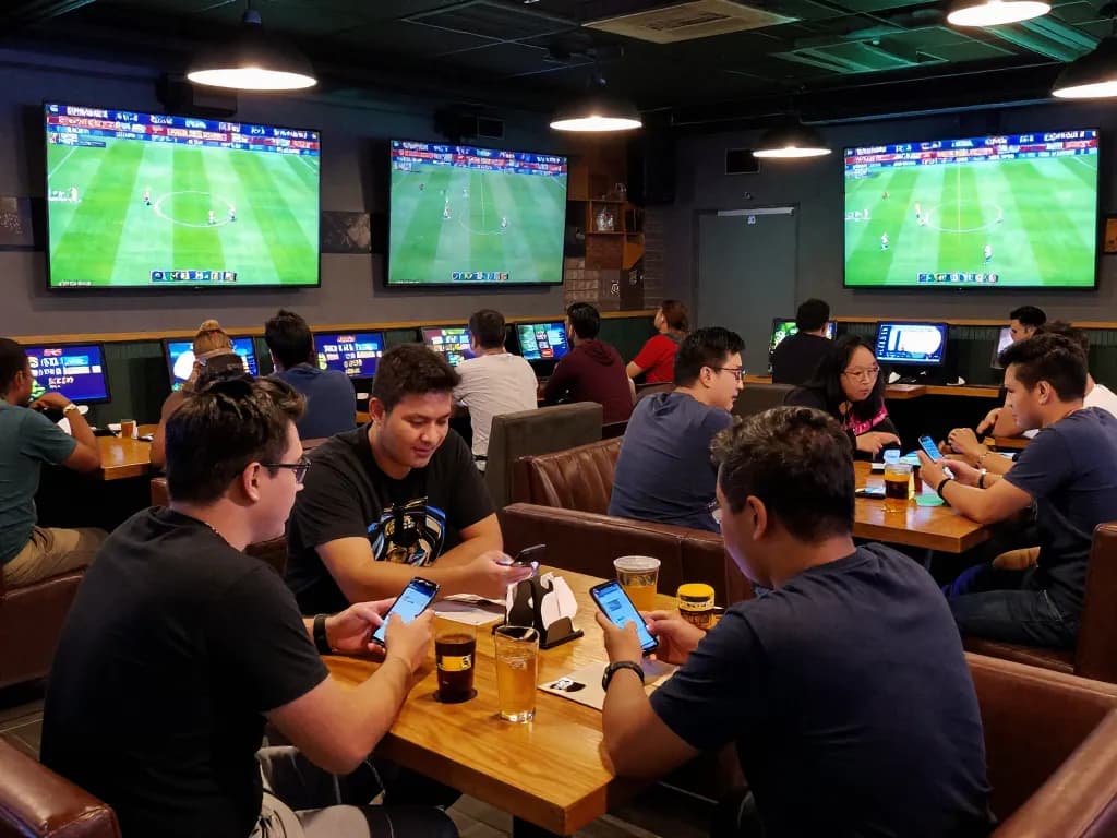 Captivating sports betting scene showcasing patrons placing bets on Bola Online in a lively sports bar.